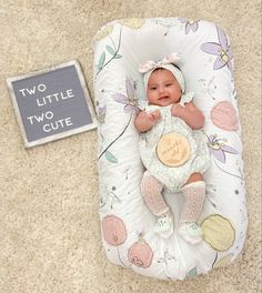 a baby is laying on a pillow next to a sign that says two little cute