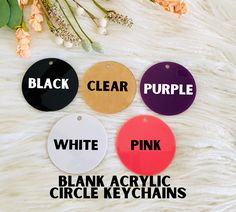 black, clear, pink, and white acrylic circle keychains with text on them