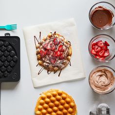 a waffle cake with chocolate and strawberries on it next to other desserts