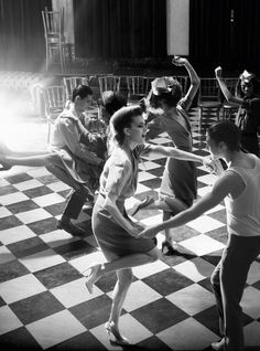 a group of people dancing on a checkered floor