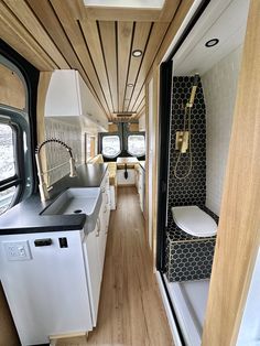 an interior view of a tiny home with wood flooring and white cabinets, along with black counter tops