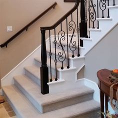 a white staircase with wrought iron handrails and carpeted flooring in a home