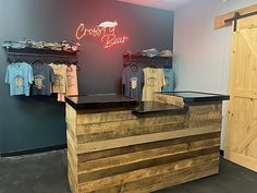 the front desk of a clothing store with shirts on display