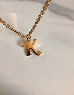 Letter K necklace, set on a stainless steel ,golden color chain. With addition cost there is an option to add a white freshwater pearl, as a charm, next to the letter. 6 mm, white round pearl Kindly choose your option. Beautiful spiritual gift. chain length 19' Please make sure you to pay attention to the size of the pendant. I have added pictures next to 25 cent coin, and measurement tape.  Need a different length just write it to me in the "message to the seller" box of the order form. **LIMIT Elegant Metal Initial Pendant Necklace, Personalized Gold Initial Necklace In Metal, Elegant Gold Stainless Steel Initial Necklace, Elegant Stainless Steel Initial Pendant Necklace, Minimalist Gold Stainless Steel Name Necklace, Gold Minimalist Initial Necklace In Stainless Steel, Minimalist Gold Stainless Steel Initial Necklace, Elegant Hypoallergenic Initial Pendant Charm Necklace, Elegant Hypoallergenic Stainless Steel Charm Necklaces