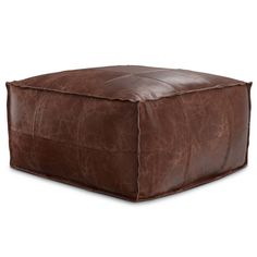 a brown leather square ottoman sitting on top of a white floor