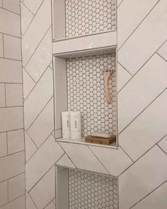 a bathroom with white tile and hexagonal tiles on the wall, along with toiletries