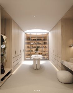 a walk in closet with a round table and white stools next to the counter