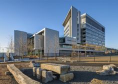 a large building sitting next to a park filled with rocks and benches in front of it