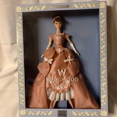 a barbie doll in a box on a white sheet with a blue border around it