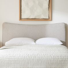 a bed with white pillows and a painting on the wall above it