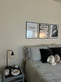 a bed with two pictures on the wall above it and a stuffed animal sitting on top