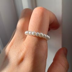 a woman's hand with a ring made out of pearls on top of it