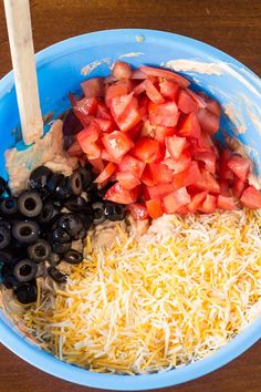 a bowl filled with cheese, black olives and tomatoes next to other food items