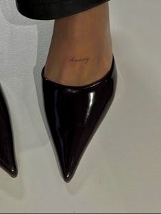 a woman's foot with a small tattoo on her left ankle and black heels