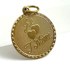 VINTAGE COSTUME JEWELRY CHARM ITEM DESCRIPTION This listing is for a vintage brass metal charm with the French saying Je T'Aime (I love you) and two hearts. I added a modern jump ring to the charm so it can be worn right away. A sweet vintage brass charm which you can add to a bracelet or necklace chain. I have two sizes of Je T'Aime charms, this is the smaller size. Vintage old stock and never worn. Any minor flaws / slight tarnish from age and storage only. Link to larger sized charm: https:// Vintage Engraved Brass Charms, Vintage Charm For Valentine's Day Gift, Vintage Collectible Charms With Round Pendant, Vintage Yellow Gold Charms For Anniversary, Vintage Yellow Gold Charms For Gift, Vintage 14k Stamped Charms For Gift, Vintage Yellow Gold Charms Stamped 14k, Vintage 14k Stamped Charms As Gift, Vintage 14k Stamped Yellow Gold Charms