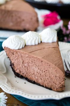 a slice of chocolate pie on a plate with a fork and flowers in the background