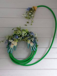 two green hoses attached to the side of a white house with flowers on them