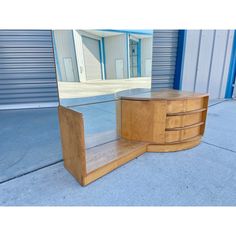 a large mirror sitting on top of a wooden table next to a building with shutters