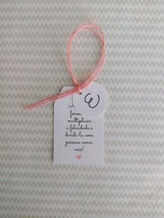 a white tag with a pink string attached to it on a beige and white wall