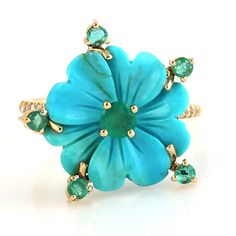 a blue flower ring with green stones on it's center and two diamonds around the middle