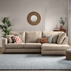 a living room with a sectional couch and round mirror