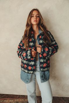 a woman standing in front of a wall with her hands on her hips and looking at the camera