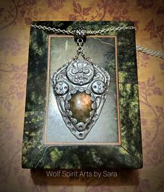 This beautiful shield-style talisman merges the beauties of Elven and Celtic design. This piece showcases a gorgeous and flashy Purple Sunset Labradorite stone! The design also features recessed and flowy filigree details upon a raised circular element; there's also a flower design which could also double as a Celtic cross-like detail! It also has a decorative bail! It's been highlighted with pearl pigment to give it a shiny metal feel, darker pigments for an oxidized look, and it's been sealed Gothic Pendant Jewelry For Larp, Polymer Clay Crystal Pendant, Purple Amethyst Amulet Jewelry, Polymer Clay Goddess Pendant, Labradorite Amulet Pendant Necklace, Elven Jewelry, Purple Sunset, Wolf Spirit, Purple Labradorite