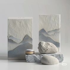 two white boxes sitting next to each other on top of a table covered in rocks