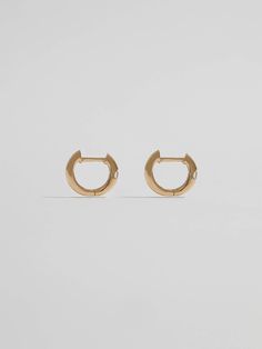 A hint of shine. Crafted from 14Kt gold, these huggie earrings are adorned with a single CZ stone that catches the light beautifully. Understated and unique, they can be worn alone or mixed with more maximalist styles. 14kt Yellow Gold 7.7mm Diameter 1.7mm Wide 1.11gr Made in Italy Materials Globally Sourced Tarnish Resistant White Gold Huggie Diamond Earrings, Tarnish-resistant White Gold Huggie Diamond Earrings, Tarnish Resistant Huggie Diamond Earrings For Anniversary, Formal Huggie Earrings With Prong Setting, 14k Gold Huggie Earrings With Vvs Clarity Diamonds, Modern Round Huggie Earrings With Prong Setting, Yellow Gold Huggie Jewelry With Single Diamond, Classic Gold Huggie Earrings With Brilliant Cut, Small Hoop Earrings With Single Diamond In 14k Gold