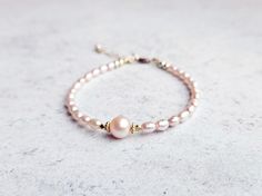 This gorgeous bracelet is made from natural rice shaped pink freshwater pearls with a round AAA grade pink pearl at the center framed by vermeil beads.  The pearls are dainty and distinctively pink, perfect for stacking with any bracelets from my shop! All finishings are gold filled, making the bracelet tarnish resistant and suitable for everyday wear. The length is 6.5 inches with 1 inch extension chain. Please message me if you need a customized size or without extension chain, I need to confi Pink Pearl Bracelet With Pearl Charm, Adjustable Pink Pearl Bracelet With Pearl Drop, Pink Pearl Drop Bracelet For Wedding, Pink Pearl Bracelet With Pearl Drop, Pink Pearl Drop Bracelet As Gift, Pink Pearl Bracelet Gift, Delicate Pink Pearl Bracelet As A Gift, Delicate Pink Pearl Bracelet As Gift, Delicate Pink Pearl Bracelet For Gift