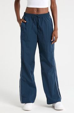 Throwback '70s style and a useful watrer-repellent finish lend style and function to these sporty nylon pants embroidered with a classic Swoosh logo. 30" inseam; 21" leg opening; 13" front rise; 16" back rise (size Medium) Elastic/drawstring waist Side-seam welt pockets; back welt pocket Water repellent 100% nylon Machine wash, tumble dry Imported Nike Stretch Nylon Bottoms, Nylon Wide Leg Parachute Pants For Sports, Wide Leg Nylon Parachute Pants For Sports, Nike Athleisure Parachute Pants For Sports, Nike Nylon Bottoms With Elastic Waistband, Athleisure Nylon Parachute Pants, Nike Nylon Long Pants, Nike Nylon Bottoms, Casual Nike Parachute Pants