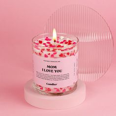 a candle that is sitting on top of a stand with pink and red confetti