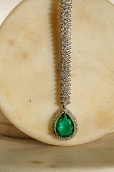 Enhance your elegance with the Safi Diamanté Accent Maang Tikka, a radiant piece crafted in a rhodium-plated silver finish. Available in stunning emerald green or sapphire blue, this exquisite maang tikka features a paved setting with glistening white diamante AD stones complemented by teardrop-shaped stones in your chosen hue. Its smaller size ensures a flattering fit for all face sizes, designed perfectly to complement our Sharmine necklace set. Key Features: Elegant Design: Paved setting with Emerald Maang Tikka, Elegant Green Stone Jewelry, Fine Jewelry For Evening In Green, Fine Green Jewelry For Evening, Fine Green Jewelry For Evening Wear, Emerald Jeweled Jewelry For Parties, Exquisite Teardrop Jewelry For Party, Elegant Jeweled Emerald Jewelry, White Gold Party Jewelry With Stones