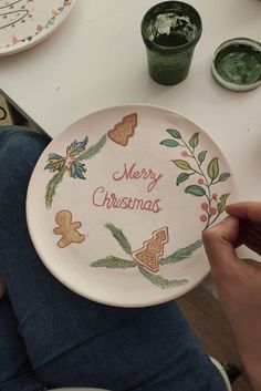 a person holding up a plate with merry christmas designs on it