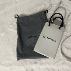 Balenciaga Mini Shopping Phone Holder Bag In White Squared Calfskin With Long Adjustable Strap. Still In Good Condition. Normal Signs Of Wear. Some Rubbings To Corner. Exterior Intact. No Tear/Cut. Snap Magnet Closure. Handles Still Sturdy. No Cracking. Interior Clean And No Smell. It Can Fit Any Phone With Other Small Items. Also Available In Vestiaire. Rolex Batman, Bags Balenciaga, Interior Clean, Coach Horse And Carriage Tote, Balenciaga Bag, Phone Holder, Mini Bag, Rolex, Calf Skin