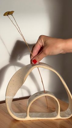 a hand is holding a piece of wood with two small sticks sticking out of it