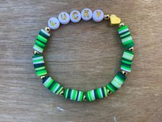 a green and white beaded bracelet with the word lucky on it's side