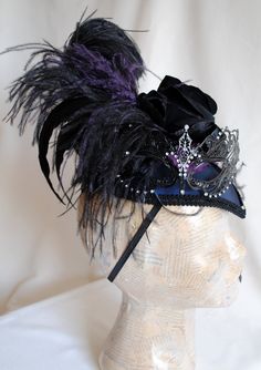 "This unique gothic-victorian masquerade headpiece was inspired by the luxurious Venice Carnival head-dresses. Created in a combination of midnight blue, black and purple. The teardrop base is covered with wonderful two-toned blue and black taffeta. I've used a gorgeous metal \"lace\" mask with rhinestones as the focal point. A glorious bouquet of flowers and feathers create a textured and one of a kind piece. A fluffy black ostrich, along with long iridescent rooster feathers and accents of pur Steampunk Headpiece For Halloween Costume, Steampunk Headpiece For Halloween Cosplay, Fantasy Costume Hats And Headpieces For Masquerade Carnival, Steampunk Costume Accessories For Carnival Cosplay, Steampunk Costume Accessories For Cosplay Carnival, Venetian Masks For Halloween Costume Party, Steampunk Masquerade Mask For Carnival Cosplay, Venetian Costume Accessories For Carnival, Fantasy Costume Accessories For Carnival Masquerade