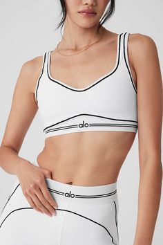 a woman in white sports bra top with black trim