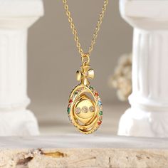 The pendant features a delicate circular frame adorned with an array of vibrant colored stones. At its heart lies a captivating surprise – a dice that gracefully rotates 360°, symbolizing the unpredictability of life's adventures. This unique piece not only reflects your sophisticated taste. Adorn yourself with this exquisite necklace, and let the world witness your flair for both beauty and whimsy.Carat Weight: 0.994 ctStone Size: 1.5,1.6,1.8,2,1.5,1.5 mmNumber of Stones: 73 Stone Color: Garnet Luxury Oval Pendant Locket Necklace As Gift, Luxury Multicolor Jewelry For Gift, Multicolor Gold Plated Jewelry For Gift, Luxury Round Pendant Locket Necklace As Gift, Round Locket Necklace With 17 Jewels For Gift, Luxury Multicolor Birthstone Jewelry, Cubic Zirconia Medallion Necklace Gift, Gift Round Pendant Birthstone Necklace With Jewels, Multi-stone Round Jewelry Gift