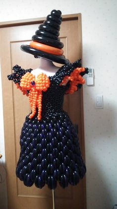 a dress made out of balloons and some sort of hat on display in front of a door