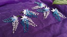 three blue and white flowers on a purple cloth