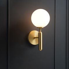 a light that is on the wall next to a black door with a white ball