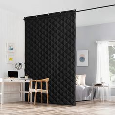 a black room divider in front of a white desk and chair with a laptop on it