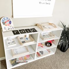 a white book shelf with books and other items on it in front of a bulletin board