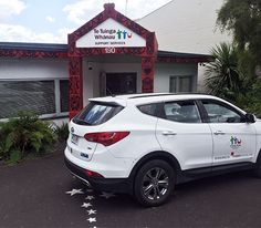 a white car parked in front of a building with stars painted on it's side