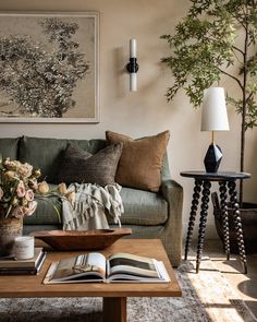 a living room filled with furniture and flowers on top of a coffee table in front of a painting