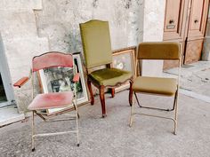 there are three chairs sitting next to each other on the ground in front of an old building