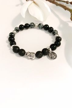 One of my best selling Bracelets with a cute antique silver elephant and OM charm.  This beautiful bracelet was designed to support those of us that tend to take on the emotional energy of others.  Snowflake  Obsidian Well-known in the crystal world as a powerful protection stone,  obsidian crystals help clear away negative energy from your psyche. Well-known as powerful Empath protection from psychic attacks and clearing of psychic smog, helping you to ground your root chakra.  Instead of hidin Handmade Black Beaded Bracelets, Bohemian Black Crystal Healing Bracelet, Bohemian Black Stretch Bracelet As Gift, Bohemian Black Stretch Bracelet As A Gift, Bohemian Black Stretch Bracelet Gift, Black Bohemian Stretch Bracelet Gift, Handmade Holistic Black Beaded Bracelets, Nickel-free Black Charm Bracelet As Gift, Nickel-free Black Charm Bracelet For Gift