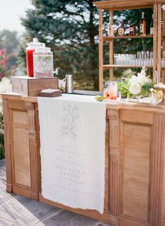 an outdoor bar set up with candles and flowers on the counter for guests to sit at